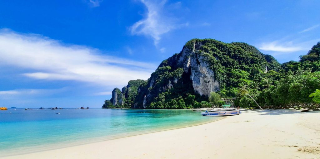 Praia de Nice Beach em Koh Phi Phi com um barco ancorado e vazia, com a fronteira e turismo fechados na Tailândia.