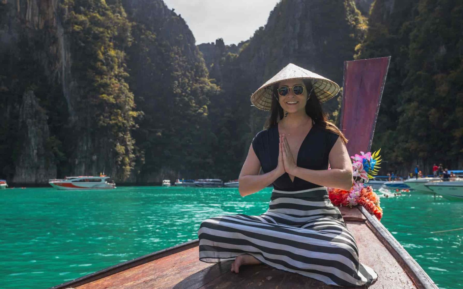 mulher sentada na frente de um long tail em Pileh Lagoon na Tailândia