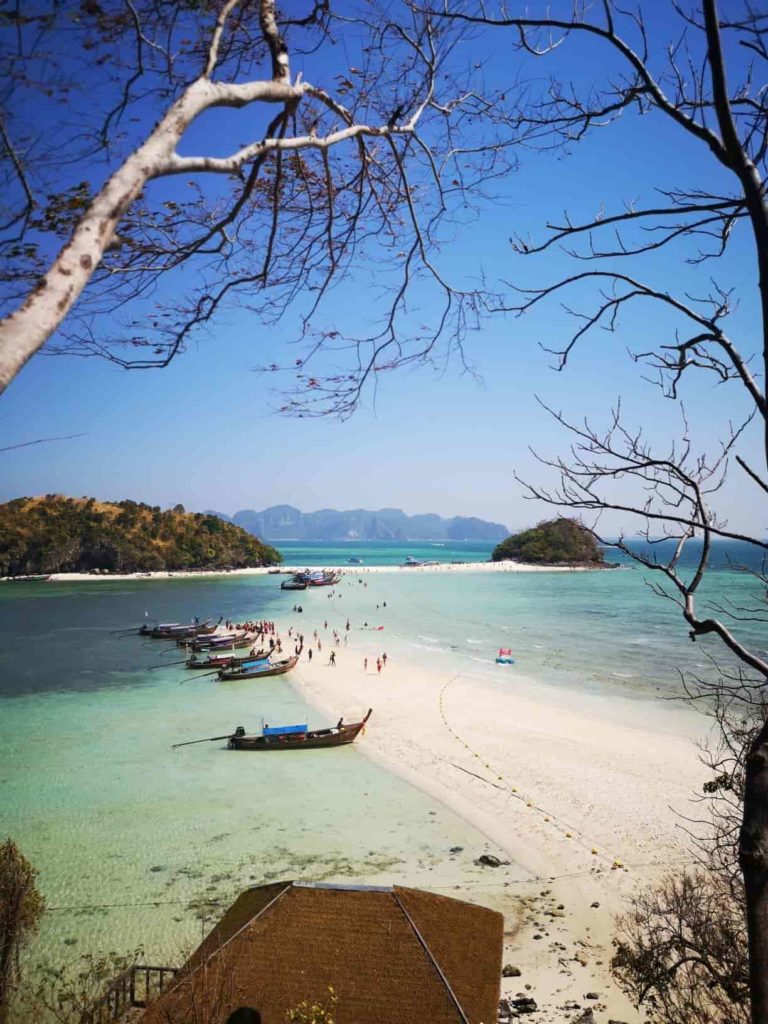 praia paradisíaca em Krabi, na tailândia, com uma faixa de areia clara e alguns barcos ancorados
