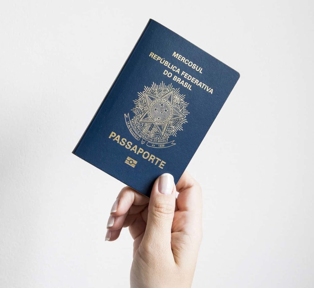 Passaporte brasileiro sendo segurado por uma mão