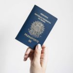 Passaporte brasileiro sendo segurado por uma mão
