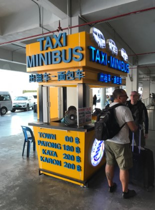 Uma foto de um estande no aeroporto de Phuket com preços das vans compartilhadas. 