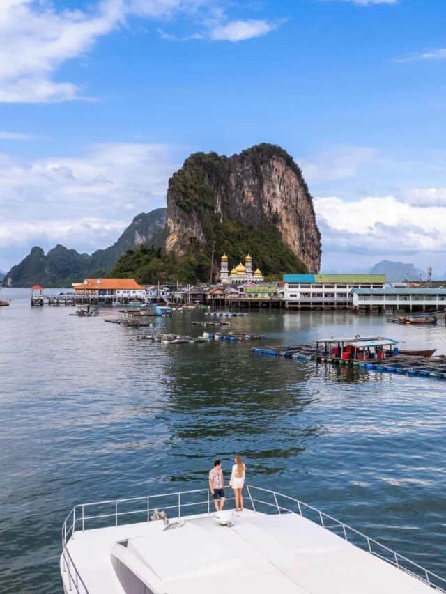 Paisagem de ilhas de Phi Phi na Tailândia, com águas cristalinas, rochas imponentes e barcos na cost.