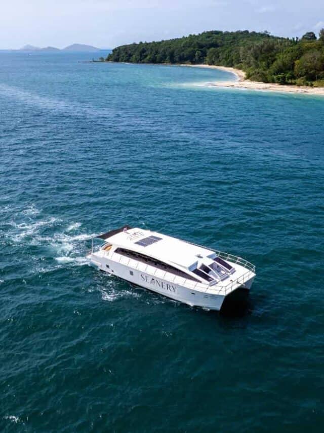 Barco navegando na água azul de Phi Phi, com ilha e vegetação ao fundo.
