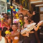 Diversão em grupo na praia com brinquedos aquáticos e sorrisos.