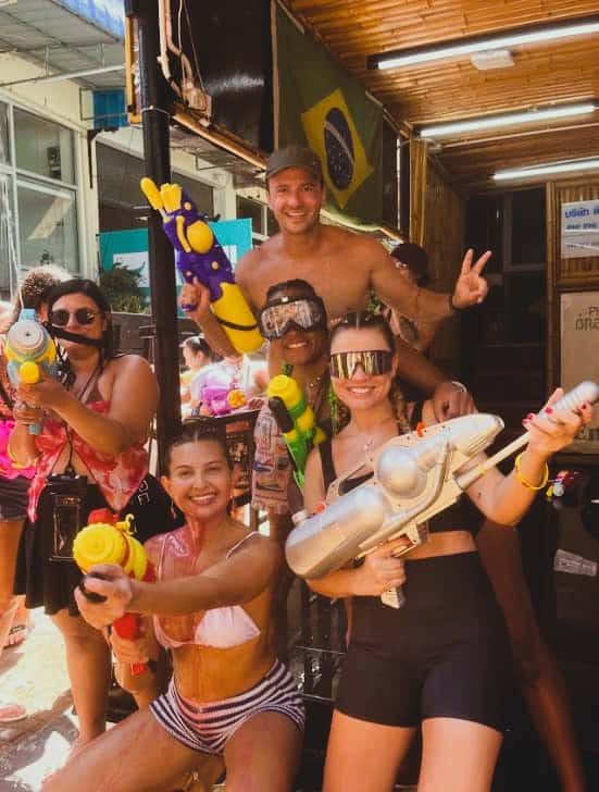 Diversão em grupo na praia com brinquedos aquáticos e sorrisos.