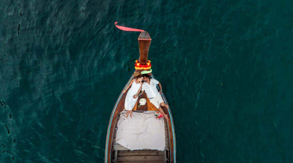 Bote tradicional em águas cristalinas de Phi Phi Brazuca, com decoração colorida e vista aérea.
