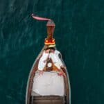 Bote tradicional em águas cristalinas de Phi Phi Brazuca, com decoração colorida e vista aérea.