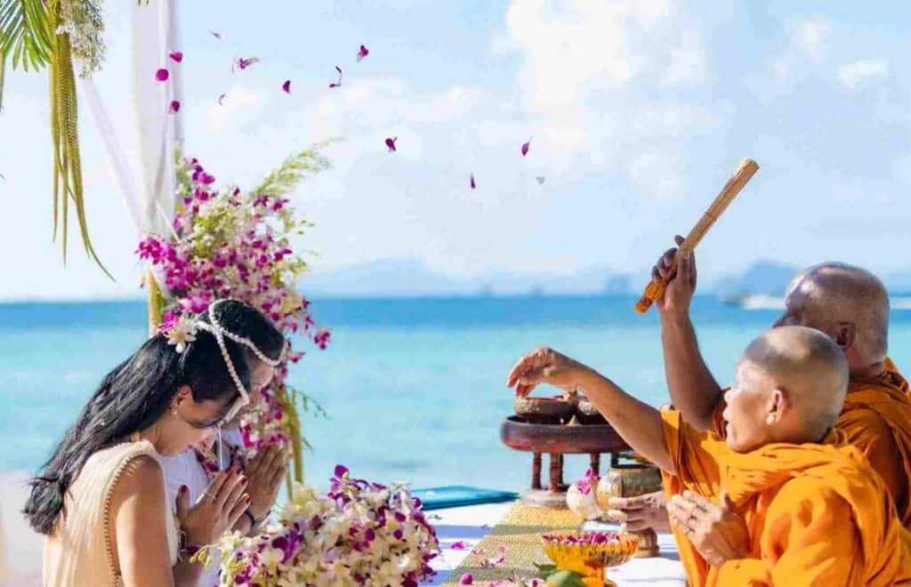 Cerimônia budista na praia de Phi Phi Brazuca com monge e devotos em celebração espiritual.