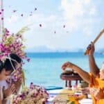 Cerimônia budista na praia de Phi Phi Brazuca com monge e devotos em celebração espiritual.