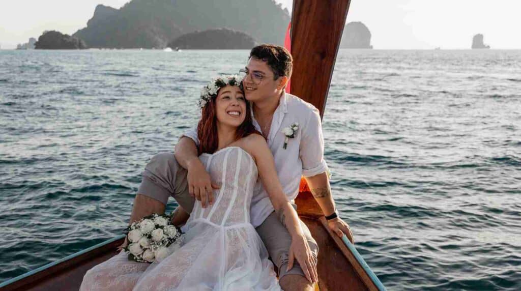 Casal feliz em cerimônia de casamento na ilha Phi Phi, com cenário paradisíaco e vista para o mar.
