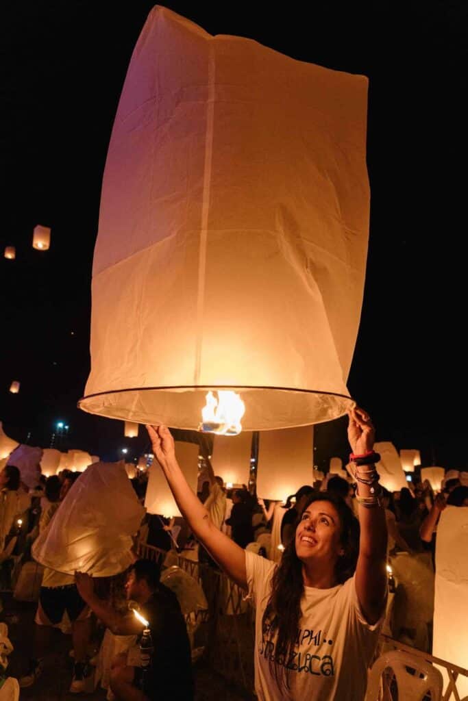 Lanterna de papel sendo lançada ao céu durante festival de lanternas na noite.