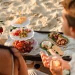 Mesa de doces e frutas na praia para casamento ao pôr do sol.