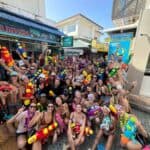 Diversão em grupo na praia de Phi Phi Brazuca, com pessoas usando fantasias e brinquedos aquáticos.